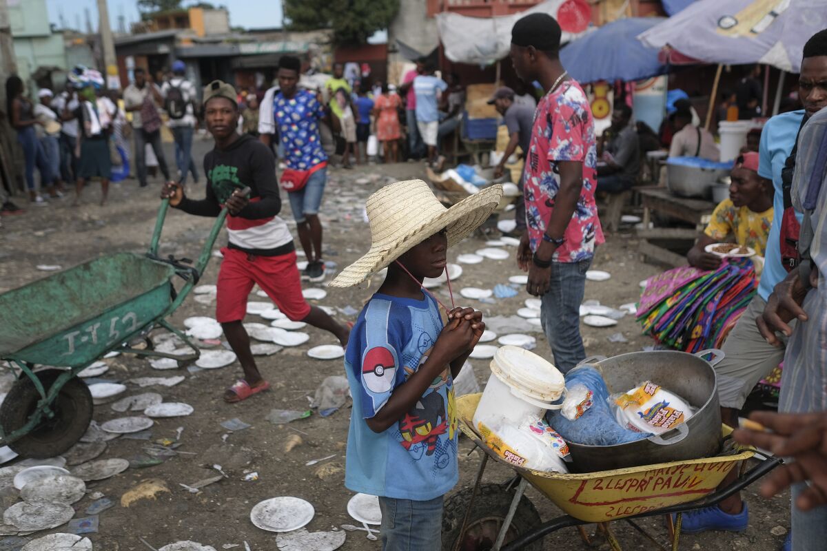 A youth waits for his cooked meal bought at a public market in Port-au-Prince, Haiti, Monday, Nov. 15, 2021. (AP Photo/Matias Delacroix)