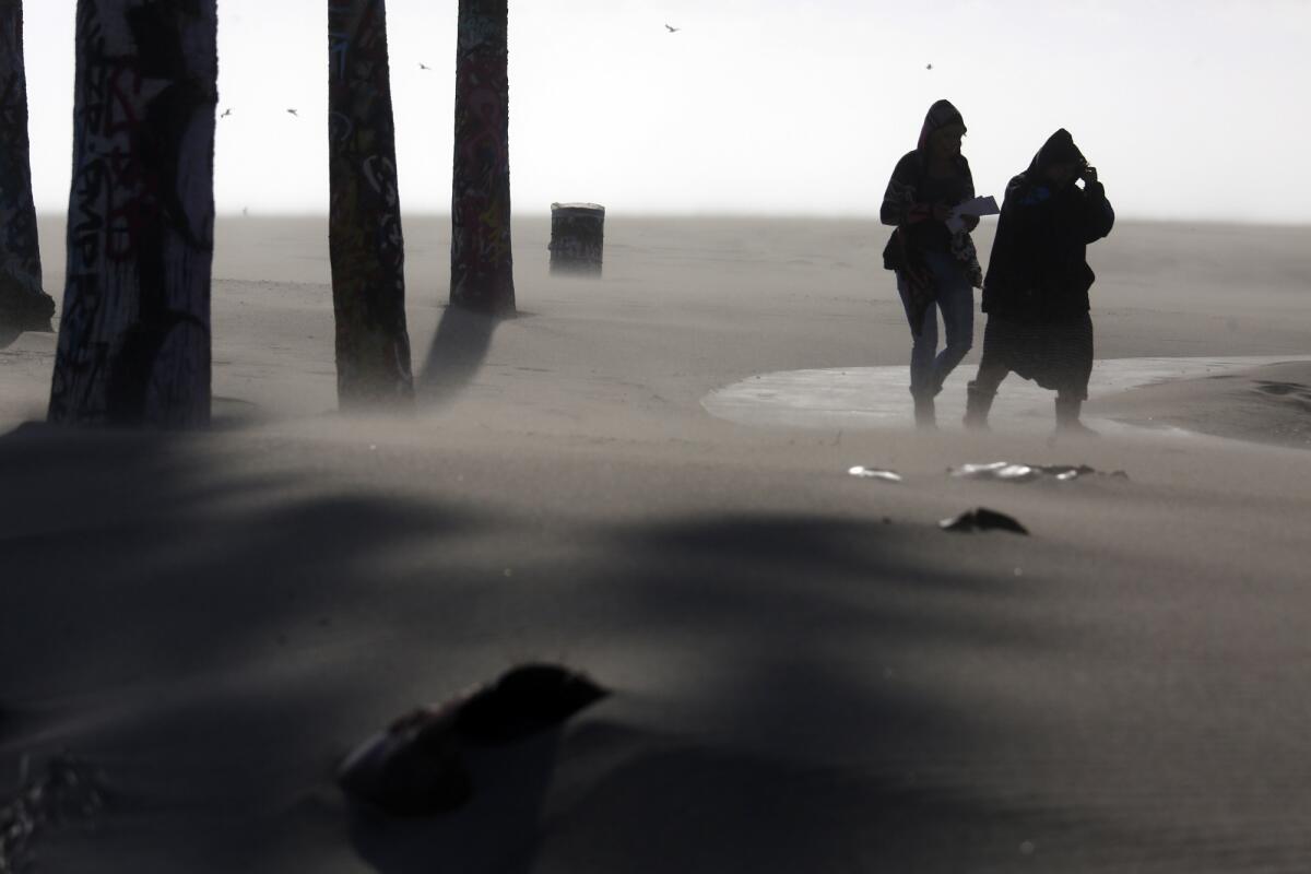 A pair of women fight powerful winds that kicked up sand at Venice Beach. (Genaro Molina / Los Angeles Times)