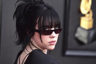 A woman with black hair wearing sunglasses and looking over her shoulder