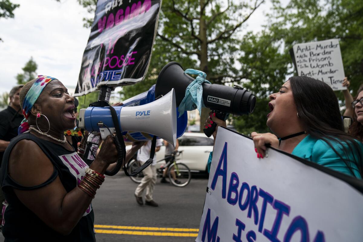 Two people demonstrating about abortion shout at each other through megaphones.