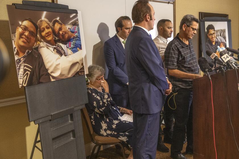 CORONA, CA-AUGUST 26, 2019: Russell French, right, addresses the media during a press conference at the Ayres Hotel in Corona to announce plans to file a civil claim against the city of Los Angeles and LAPD officer Salvador Sanchez for the shooting death of his son Kenneth French inside a Corona Costco earlier this year. At left is his wife Paola French, 2nd from right is his son Kevin French. 2nd from left is attorney Eric Valenzuela and 3rd from left is attorney Dale Galipo. Photograph at left is left to right-Kenneth French and his parents, Paola, and Russell, taken in 2019. Photograph at right is Kenneth French holding his cousin Lily DCunha, taken in 2014. (Mel Melcon/Los Angeles Times)
