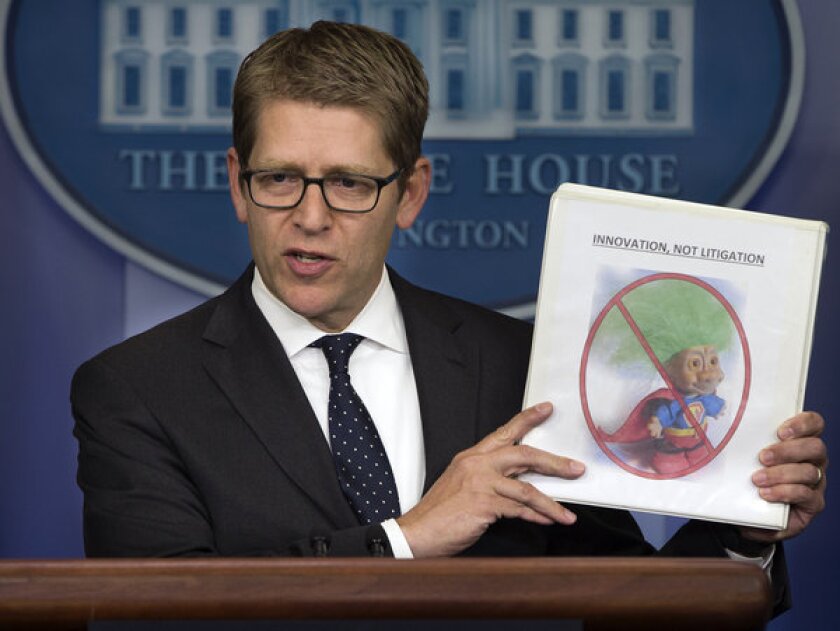 White House press secretary Jay Carney holds up a folder with an image of a troll and the words "innovation, not litigation." The Obama administration seeks to limit frivolous patent lawsuits.