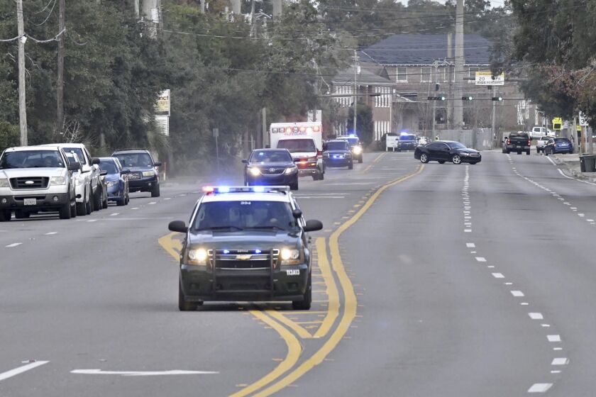 Police cars escort an ambulance after a shooter open fire inside the Pensacola Air Base, Friday, Dec. 6, 2019 in Pensacola, Fla. The US Navy is confirming that a shooter is dead and several injured after gunfire at the Naval Air Station in Pensacola. (Tony Giberson/ Pensacola News Journal via AP)