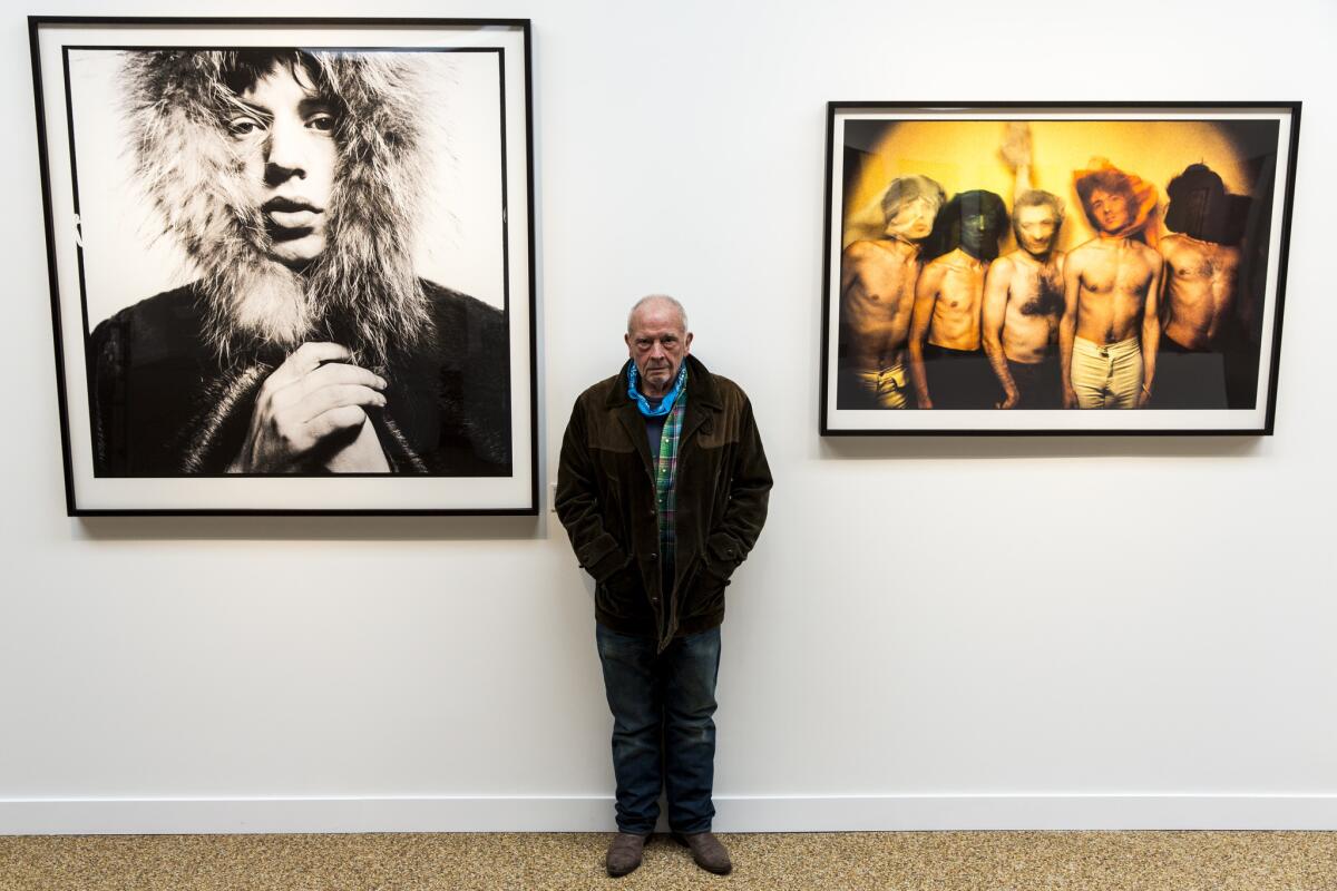 David Bailey is photographed between two of his iconic 1960s images of the Rolling Stones at the Taschen Gallery in Los Angeles.