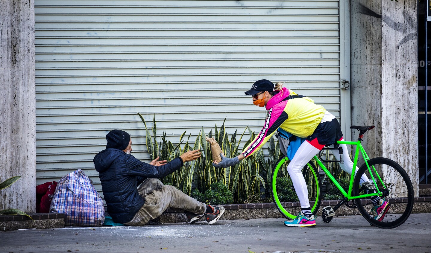Bicycle Meals volunteer Alex Gilbertson delivers a bagged meal to a homeless man in Koreatown. 