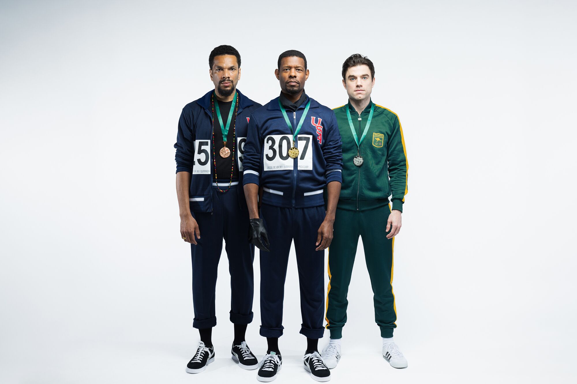 Three actors in track suits lined up left to right.
