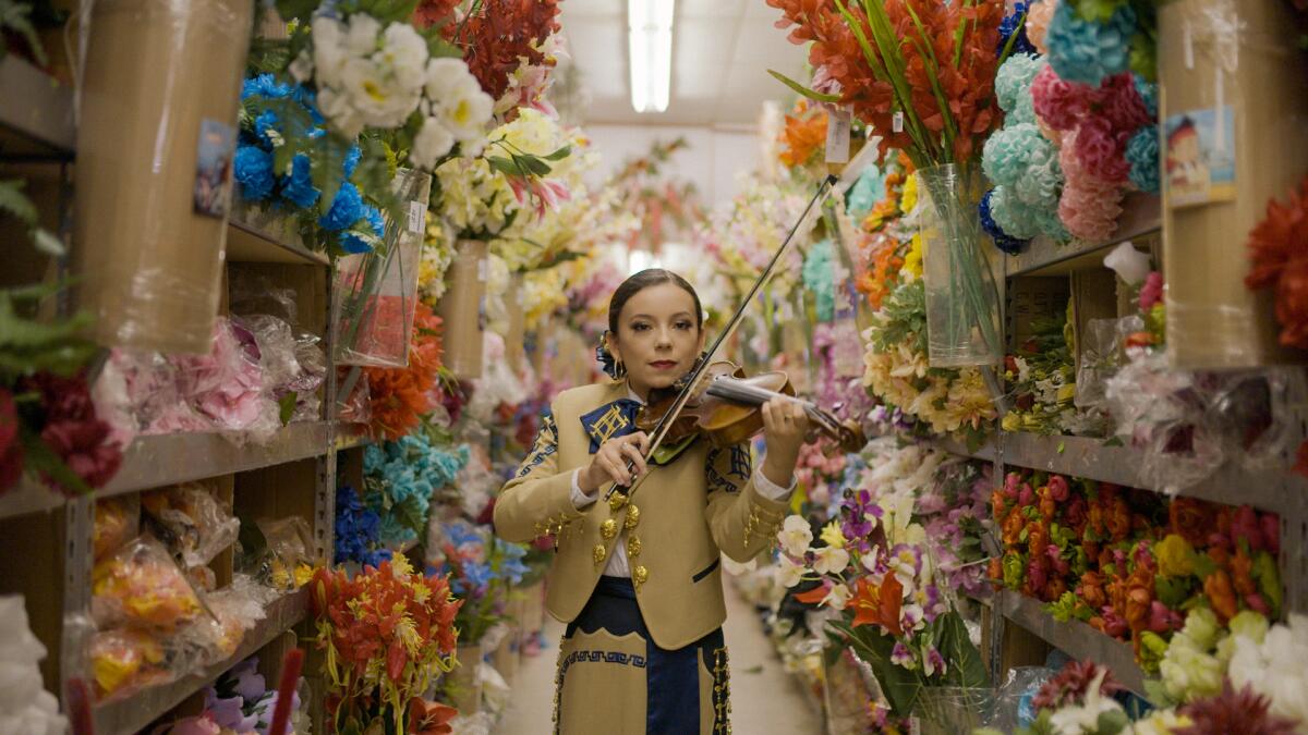 A woman mariachi plays a violin 