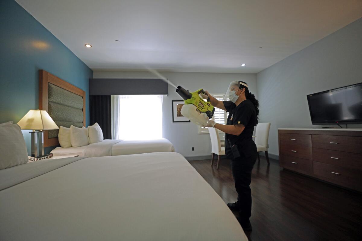 A worker at a hotel in Studio City uses a handheld machine to spray a disinfectant fog made of ethanol and hydrogen peroxide.