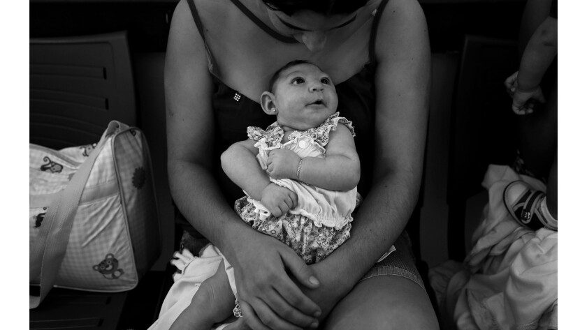 Maria Silva Floa, age 20, holds her baby, Maria Silva Alves, 2 months, who was born with microcephaly, as she waits for her daughter's physiotherapy appointment at Pedro 1 Municipal Hospital in Campina Grande, Brazil.