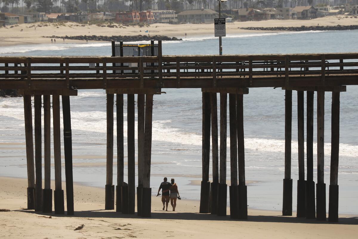 A couple walks beneath the Ventura Pier.