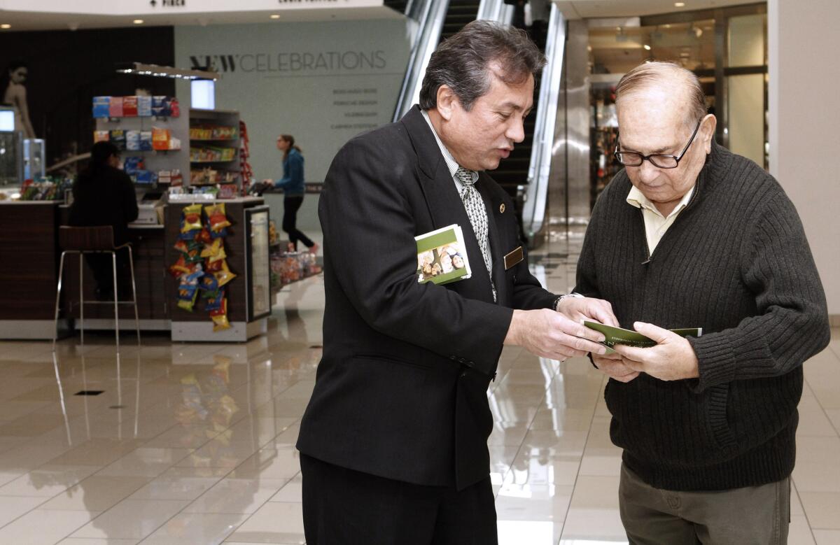 Forest Lawn Glendale advance planner Argenis Barreto, left, talks to Wadhu Bhojwani of Glendale about funeral planning at the FL kiosk at the Glendale Galleria on Friday, Feb. 7, 2014. The Forest Lawn kiosk has been at the mall next to Macy's since the beginning of 2014.