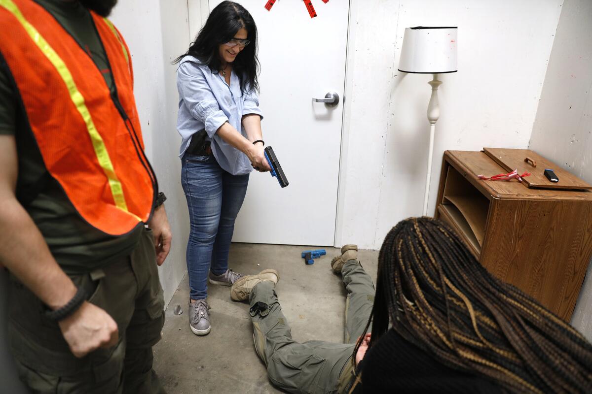 With a fake gun and a smile, Louise Gill helps fellow academy participant Norchelle Brown, bottom right, take down a special agent posing as a suspect.