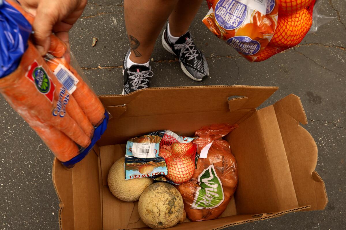  Yanira C. Ruiz, 50, looks over her box of produce she received at a food giveaway.