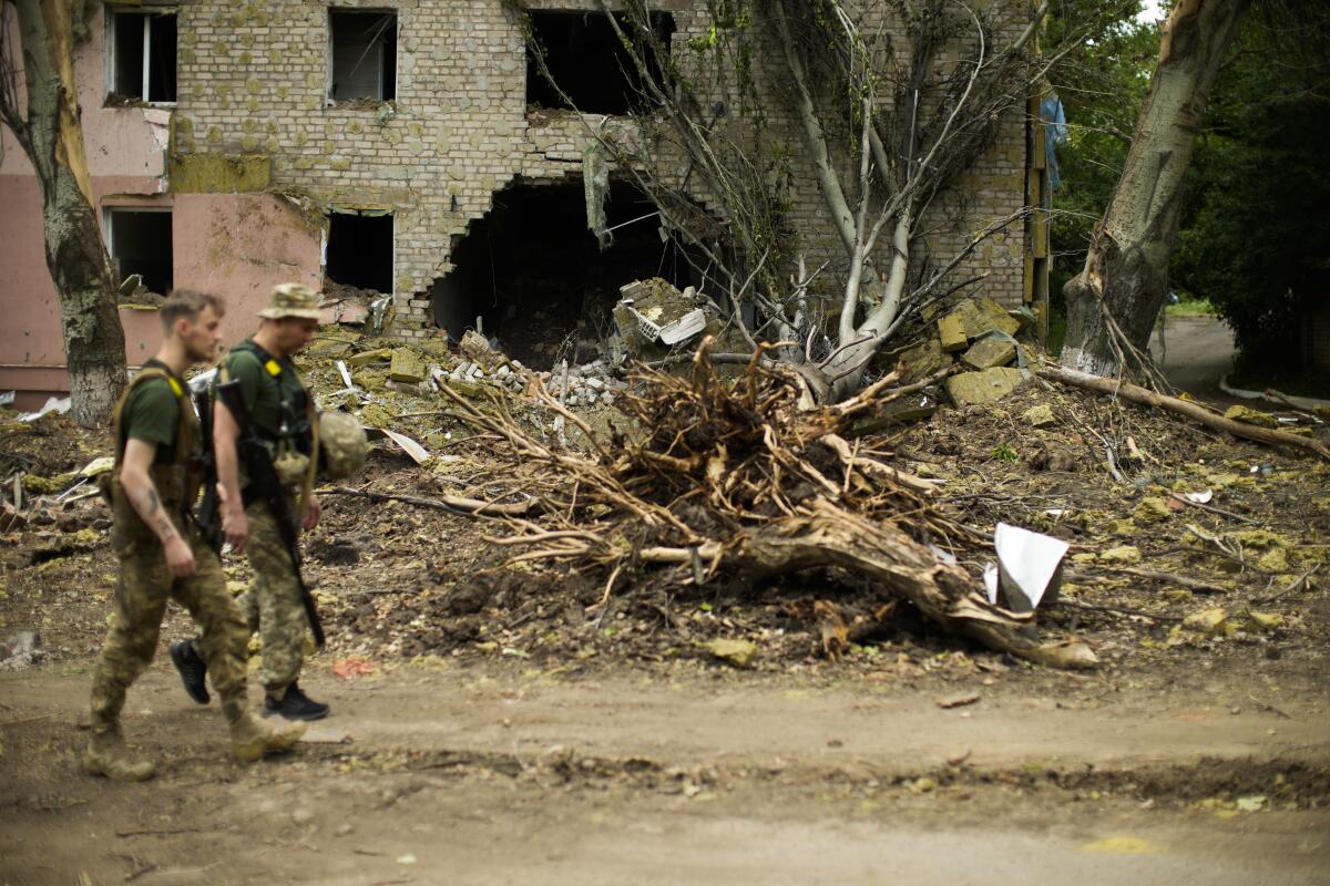 Ukrainian servicemen walking past heavily damaged building