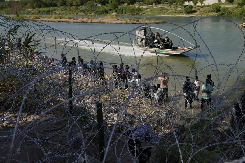 FILE - Migrants who crossed into the U.S. from Mexico are met with concertina wire along the Rio Grande, Thursday, Sept. 21, 2023, in Eagle Pass, Texas. U.S. authorities say illegal border crossings from Mexico fell 14% in October from a month earlier, following three months of big increases. The decline comes during the resumption of deportation flights to Venezuela, shortly after Venezuelans replaced Mexicans as the largest nationality appearing at the border. (AP Photo/Eric Gay, File)