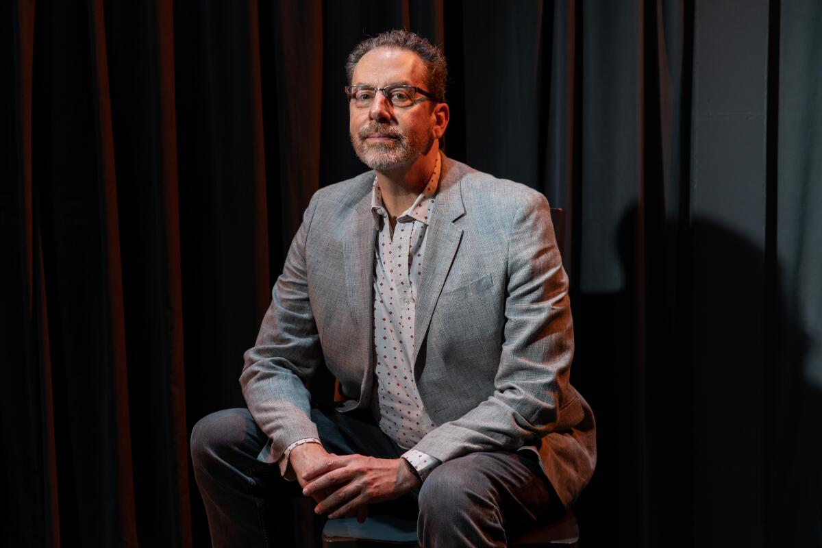 L.A. stage director Michael Michetti, wearing a gray suit, sits in the Boston Court Pasadena theater.