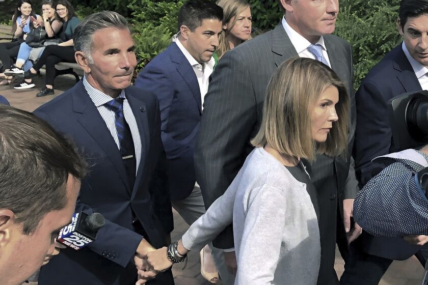 FILE - In this Aug. 27, 2019, file photo, Lori Loughlin departs federal court in Boston with her husband, Mossimo Giannulli, left, after a hearing in a nationwide college admissions bribery scandal. Giannulli has reported to prison to begin serving his five-month sentence for bribing his daughters’ way into college. Giannulli’s wife, “Full House” actor Lori Loughlin, is already behind bars for her role in the college admissions bribery scheme involving prominent parents and elite schools across the country. She began her two-month prison term late last month. (AP Photo/Philip Marcelo, File)