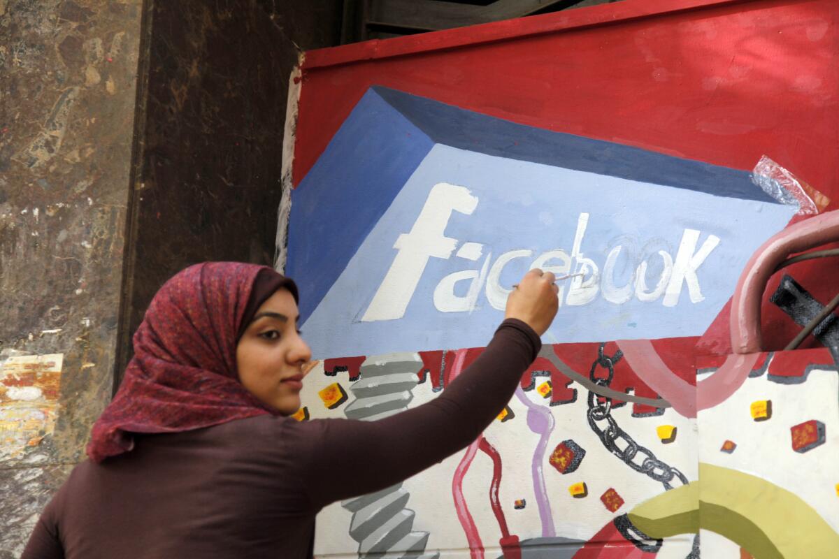 An art student paints the Facebook logo on a mural commemorating the 2011 uprising against former Egyptian President Hosni Mubarak in Cairo. Facebook says Egyptian authorities have shut down a program that was providing free basic Internet service to more than 3 million users in the country.