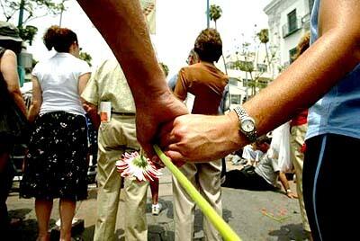 People hold hands during a memorial service at the reopening of the Santa Monica Farmers Market after the deadly crash.