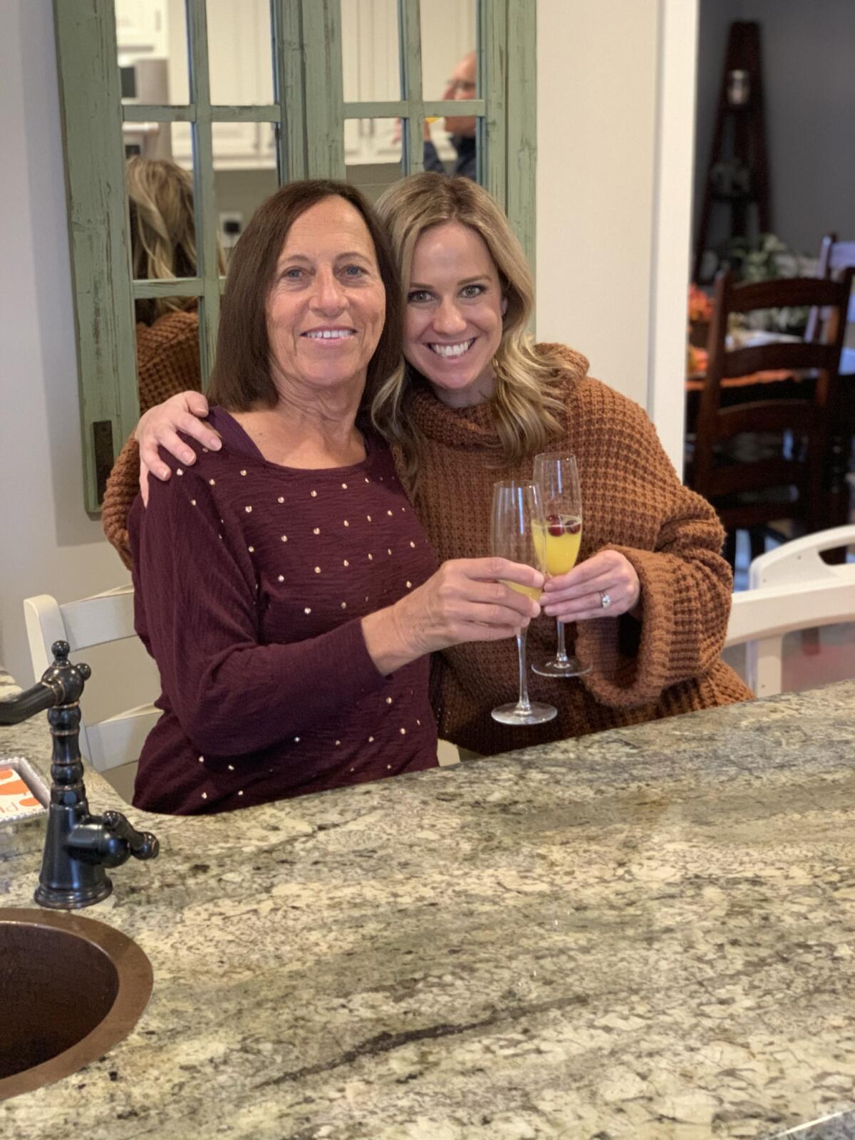 A woman and her adult daughter celebrate with champagne glasses.