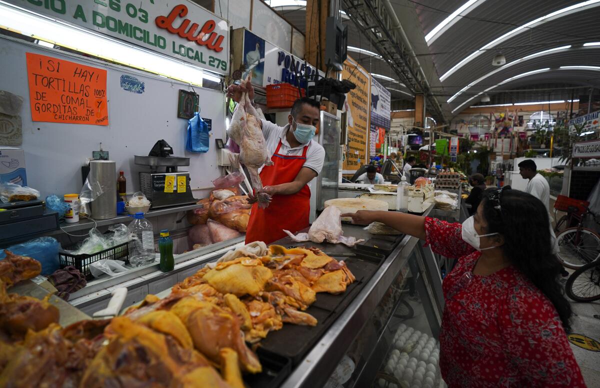 A client shops for chicken at a market in Mexico City, Tuesday, Aug. 9, 2022. Mexico's annual inflation rate rose to 8.15% in July, driven largely by the rising price of food, according to government data released Tuesday. (AP Photo/Fernando Llano)
