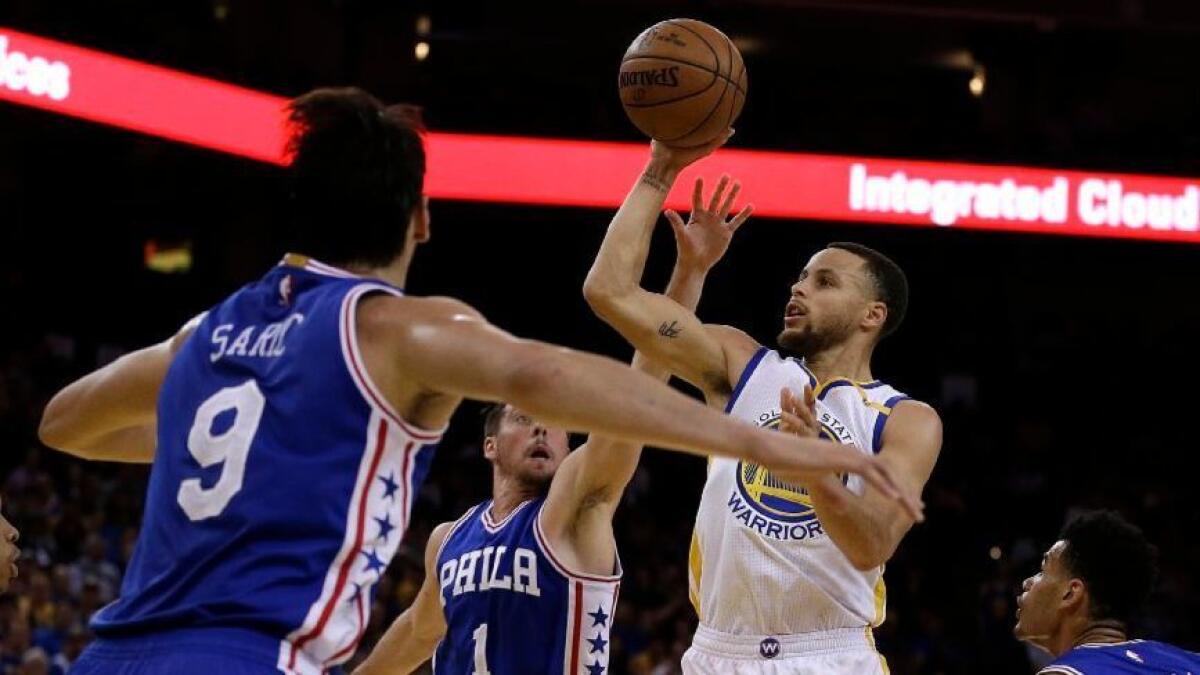 76ers' Dario Saric (9) and TJ McConnell (1) guard Golden State Warriors guard Stephen Curry (30) during the second half on Mar. 14.