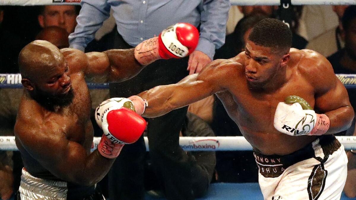 Anthony Joshua sends Carlos Takam reeling with an overhand right during their heavyweight title fight Saturday night.