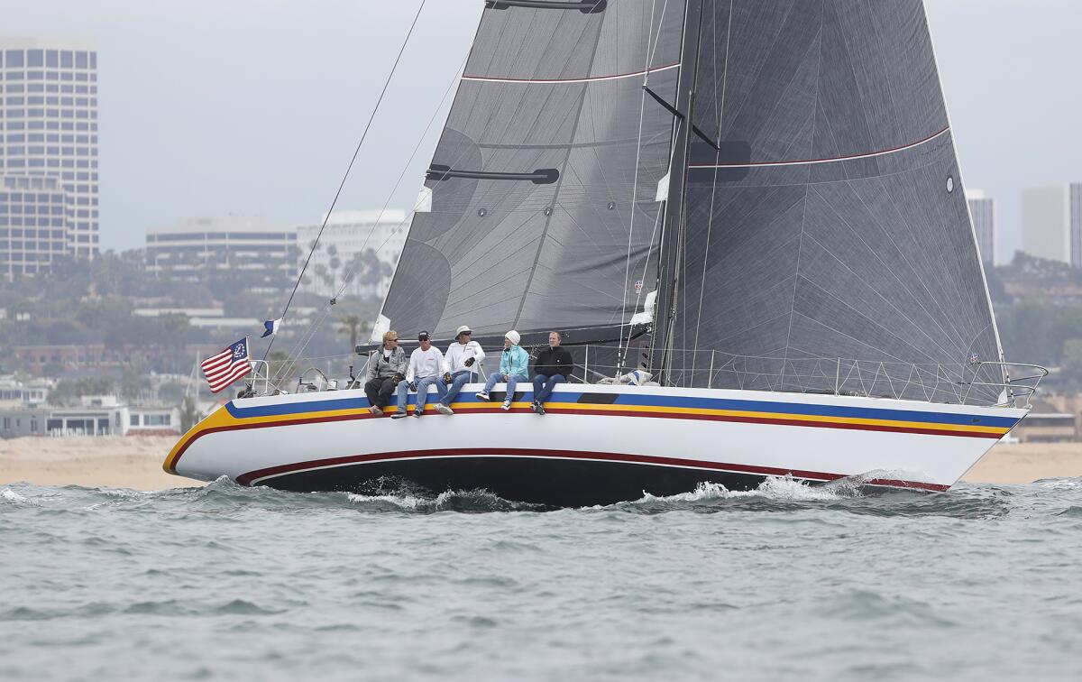 Crew members on the Amante sit on the rail during the start of the yacht race.