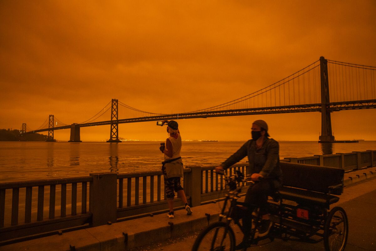 Two people in front of a red sky with the Golden Gate Bridge in the background.