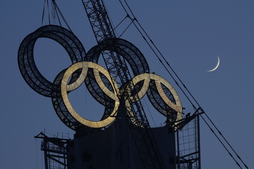 FILE - A worker labors to assemble the Olympic Rings onto of a tower on the outskirts of Beijing, China on Jan. 5, 2022. The Beijing Winter Olympics are fraught with potential hazards for major sponsors, who are trying to remain quiet about China's human rights record while protecting at least $1 billion they've paid to the IOC. (AP Photo/Ng Han Guan, File)