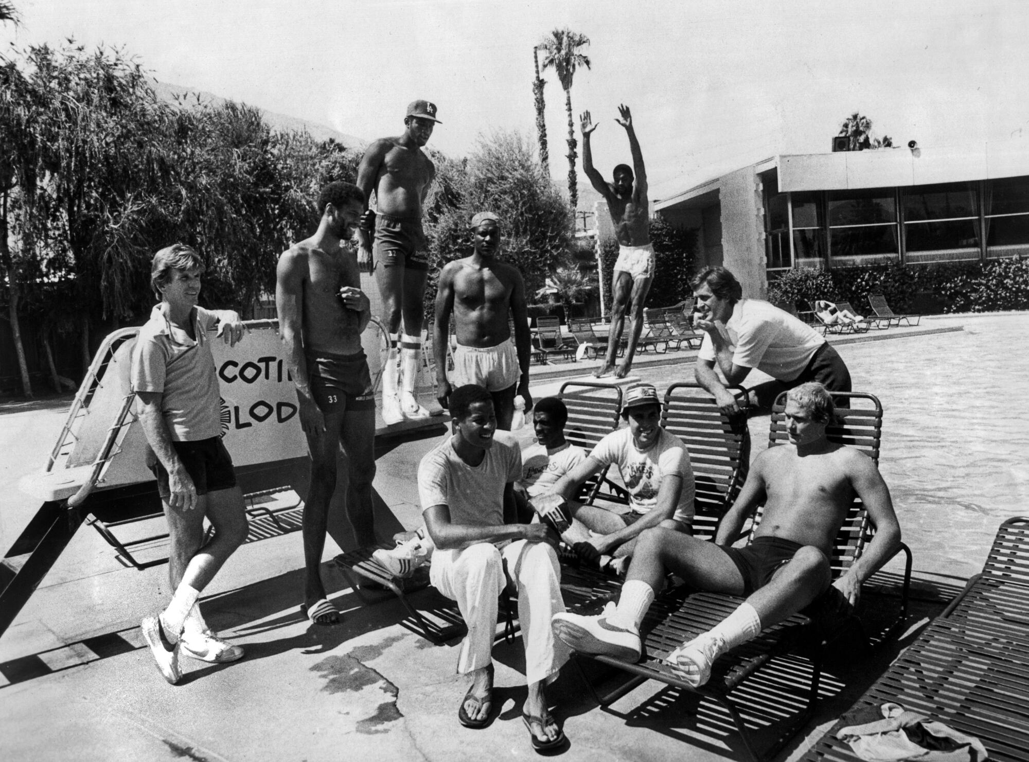 The 1980-81 Lakers cluster together next to a pool on a sunny day