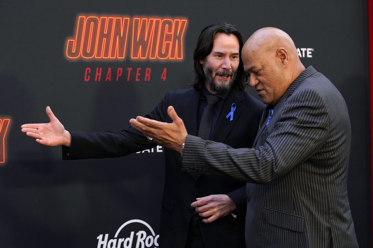 Keanu Reeves, left, and Laurence Fishburne, cast members in "John Wick: Chapter 4," walk the carpet together at the premiere of the film, Monday, March 20, 2023, at the TCL Chinese Theatre in Los Angeles. (AP Photo/Chris Pizzello)