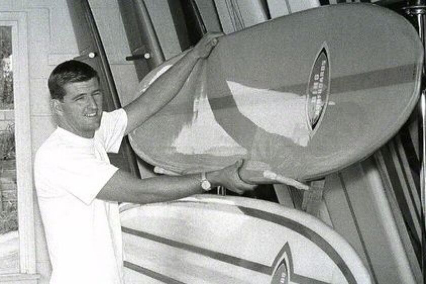 Surfing pioneer Bing Copeland, now 80, shows off some of his handiwork many years ago. Copeland was the longtime owner and boardmaker at Bing Surfboard in Encinitas.