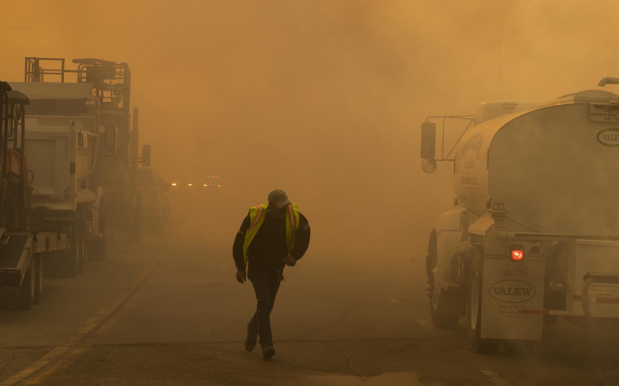 A water truck operator runs through the thick smoke of the advancing Silverado fire fueled by Santa Ana winds.