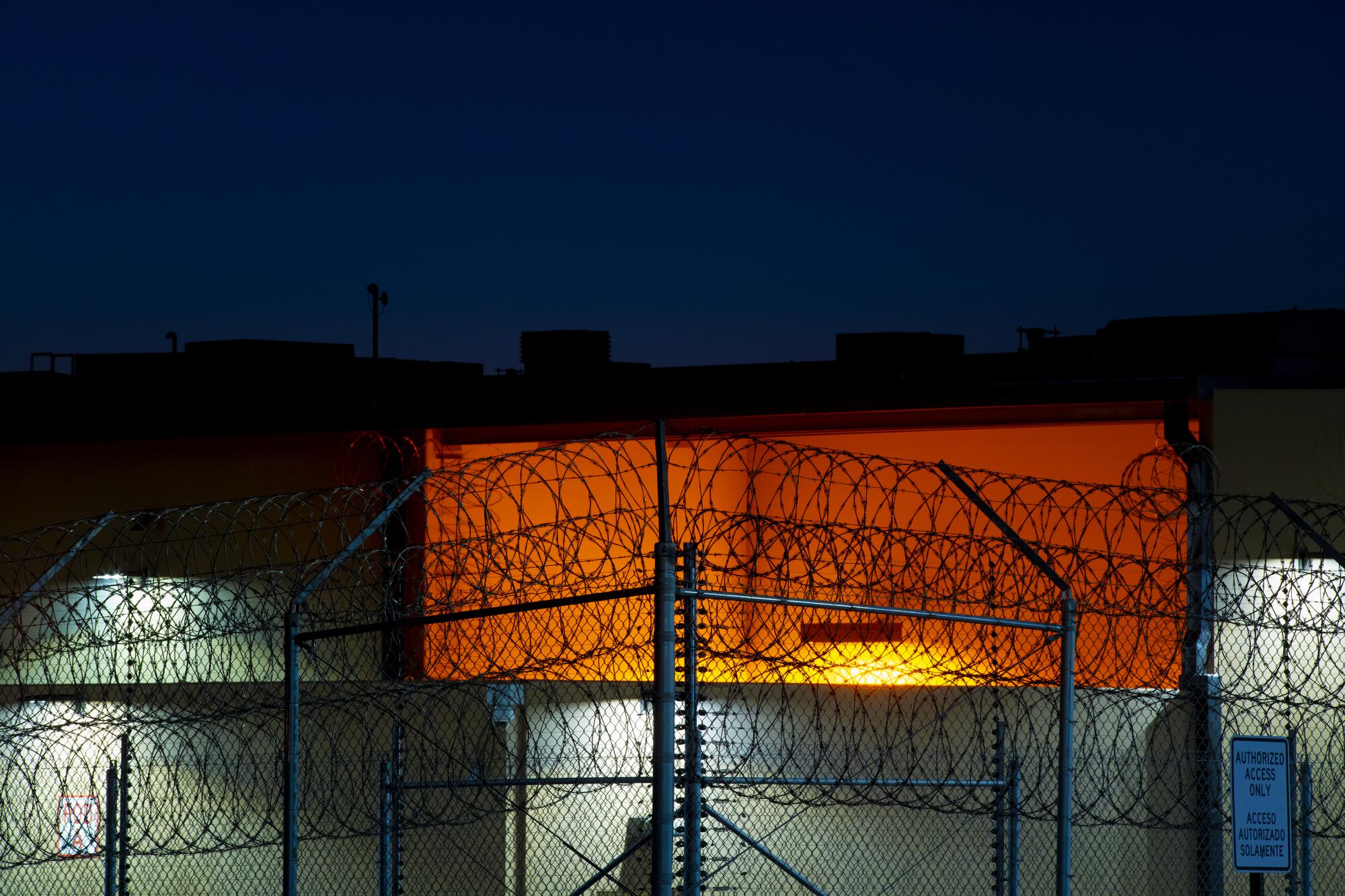 Coils of razor wire line the fence in front of Otay Mesa Detention Center, seen at night