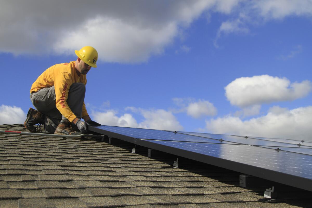 Electrician Anthony Bur works on a rooftop solar array in El Cajon in 2019.