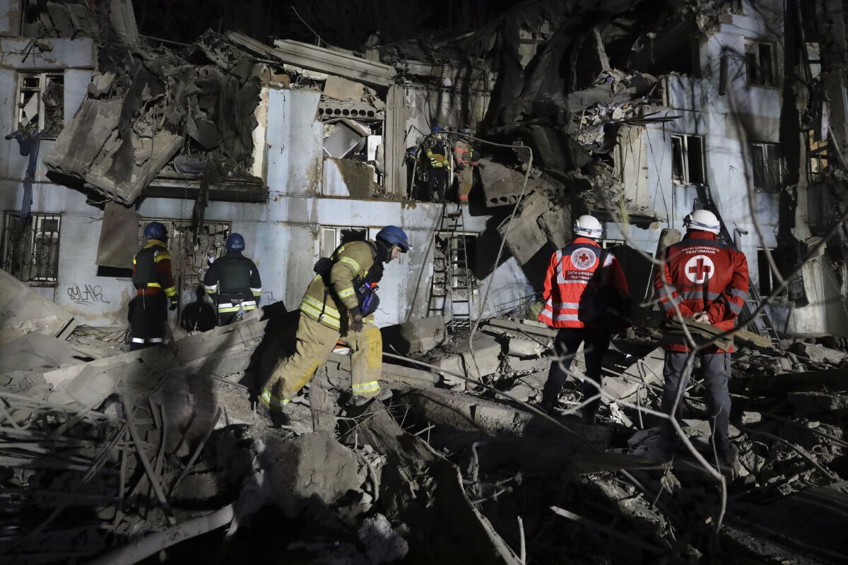 Ukrainian firefighters inspecting a house damaged by Russian shelling