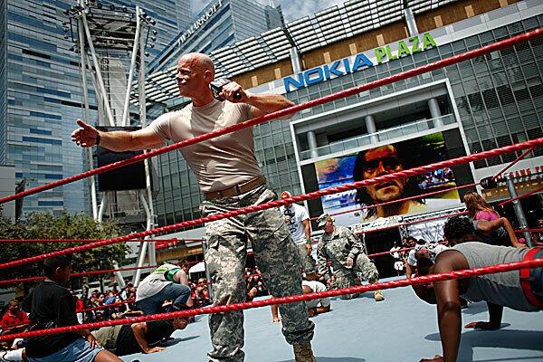 U.S. Army National Guard Staff Sgt. Ken Weichert, based in Nashville, Tenn., motivates the crowd while conducting a push-up contest between a National Guard soldier and four WWE fans as part of the World Wrestling Entertainment's Summer Slam Axxess event outside Staples Center in downtown Los Angeles.