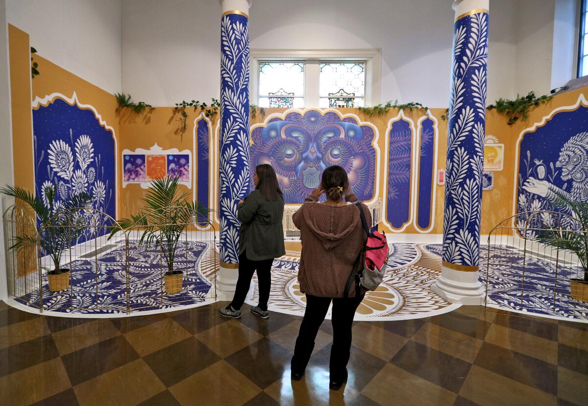 Visitors look at vibrant mythical creatures and complex geometric patterns by Mexican artist Curiot at the Fullerton Museum Center for the exhibit "Instruments of Change." The exhibit explores Latin American urban art.