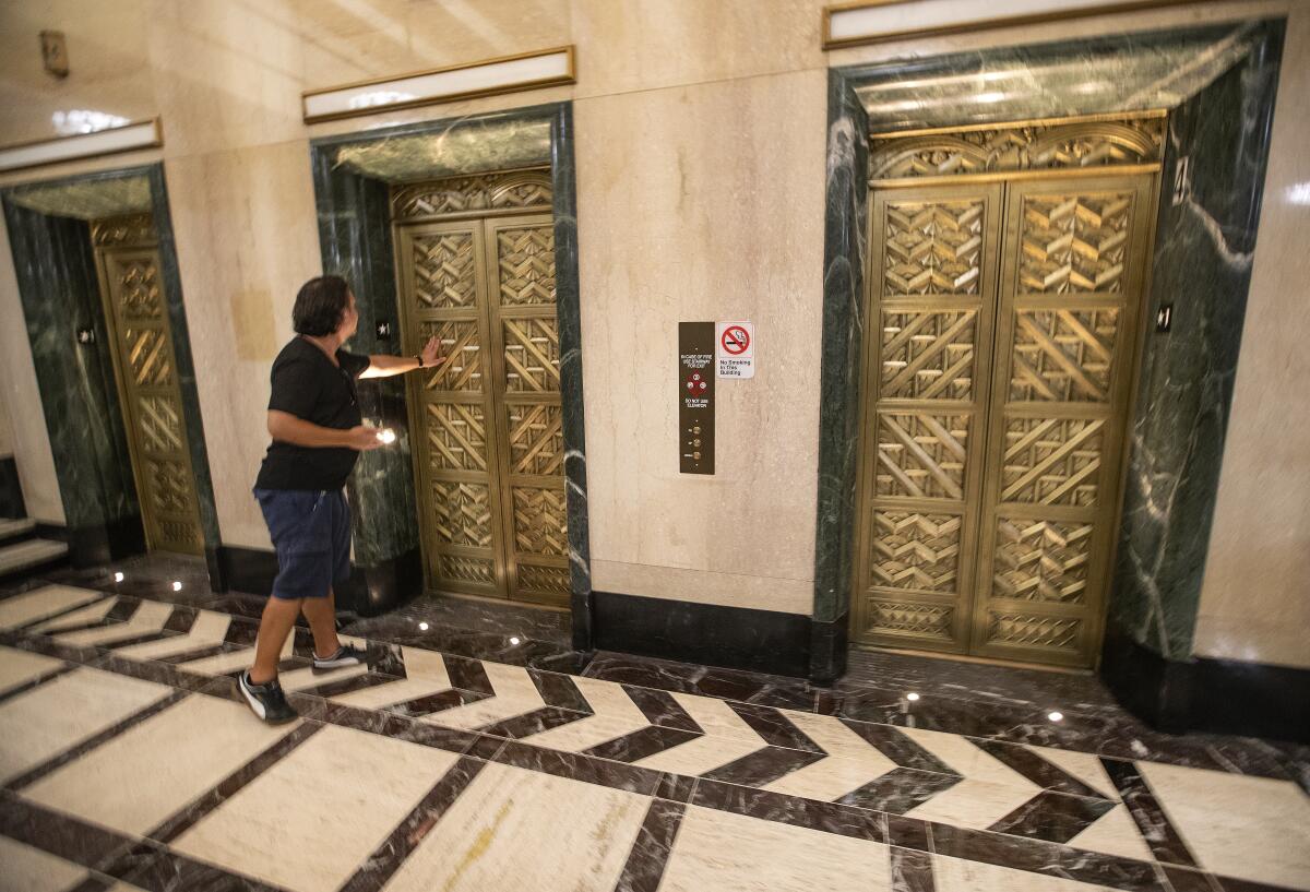 Edward Grad of Santa Monica touches a solid brass elevator door while touring the lobby of the Trust Building.