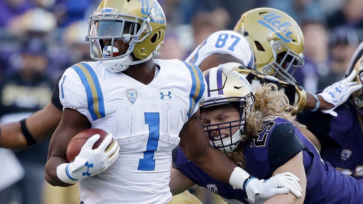 UCLA's Soso Jamabo carries the ball as Washington's Ben Burr-Kirven attempts a tackle in their game Oct. 28..