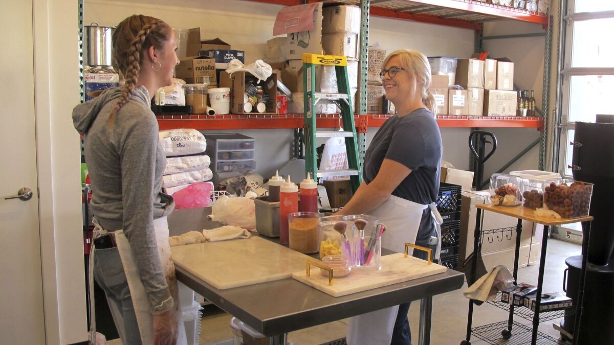 Craft doughnut shop owner Amy Pruchnic, right, talks with an employee at her busy new store in downtown Spokane, Wash, on June 8. The state's second-largest city is booming these days.