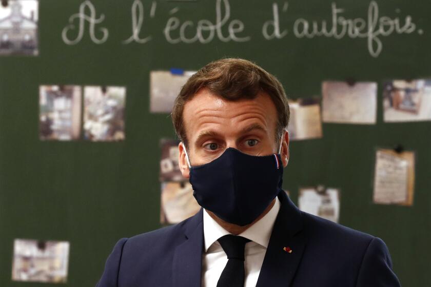 French President Emmanuel Macron, wearing a protective face mask, speaks with schoolchildren during a class at the Pierre Ronsard elementary school Tuesday, May 5 2020 in Poissy, outside Paris. Starting from May 11, all French businesses will be allowed to resume activity and schools will start gradually reopening. (Ian Langsdon, Pool via AP)