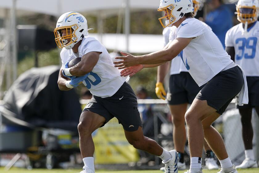 COSTA MESA, CA - JULY 28: Chargers running back Austin Ekeler (30), left, receives a hand off from quarterback Justin Herbert (10), at LA Chargers training camp at Jack R. Hammett Sports Complex on Thursday, July 28, 2022 in Costa Mesa, CA. (Gary Coronado / Los Angeles Times)