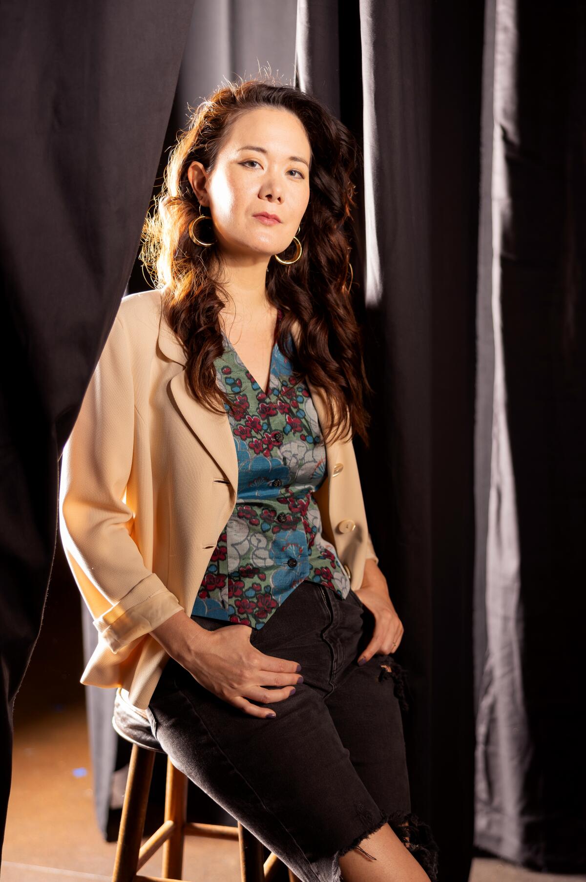 Keiko Green sits connected a stool successful beforehand of a curtain