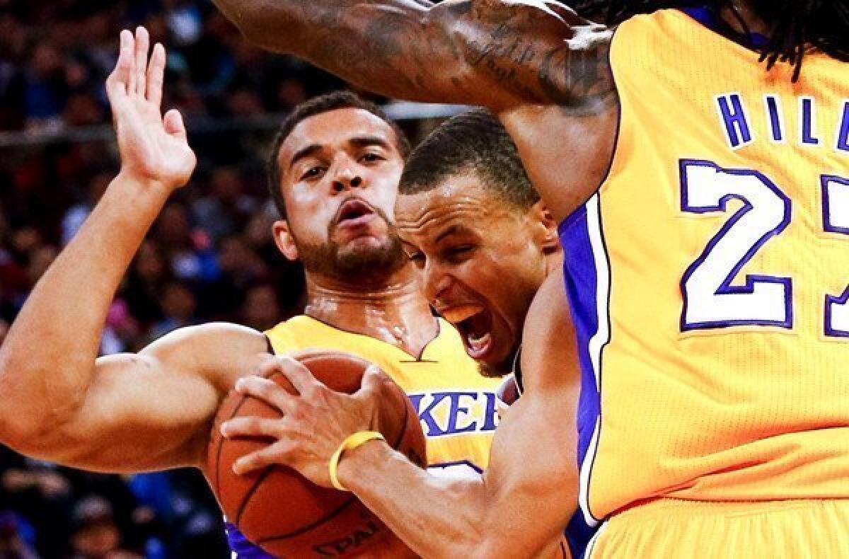 Lakers rookie Elias Harris, left, playing defense against Golden State's Stephen Curry in a preseason game.
