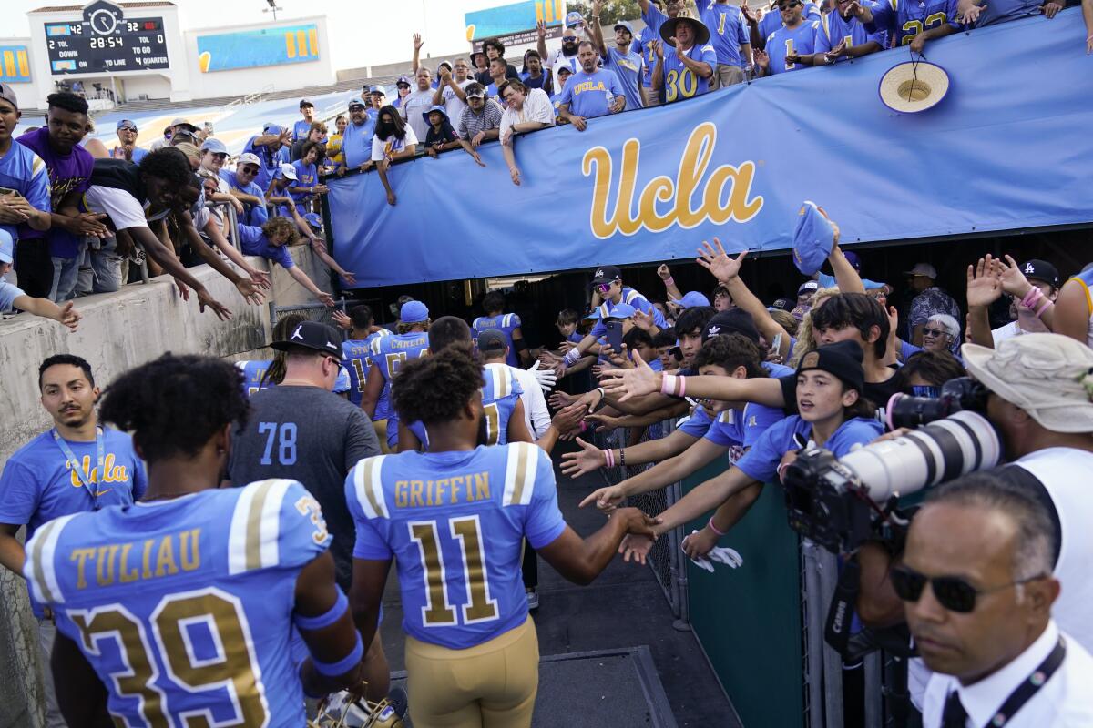 UCLA football players greet fans as they leave the field after a game at the Rose Bowl.