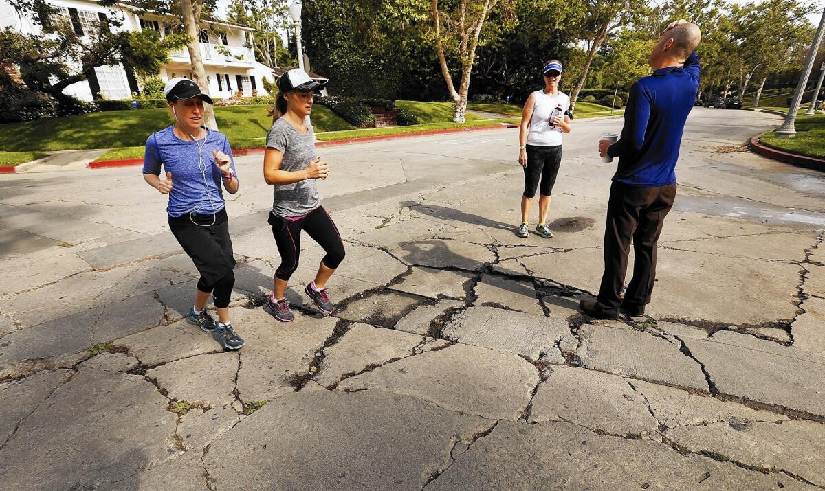 Tim Allyn, right, talks to Corrina Wright, center, about the pavement in Hancock Park. He’s been critical of former City Hall aide Carolyn Ramsay.