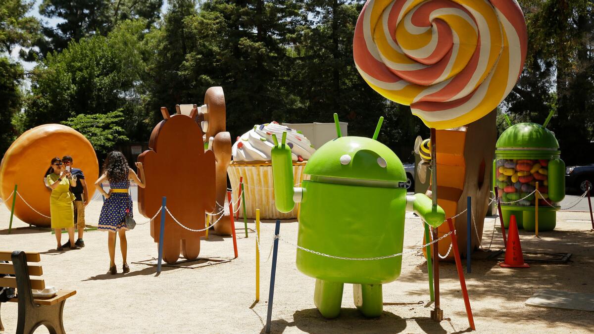 People pose by Android lawn statues at Google's headquarters in Mountain View, Calif., last week.