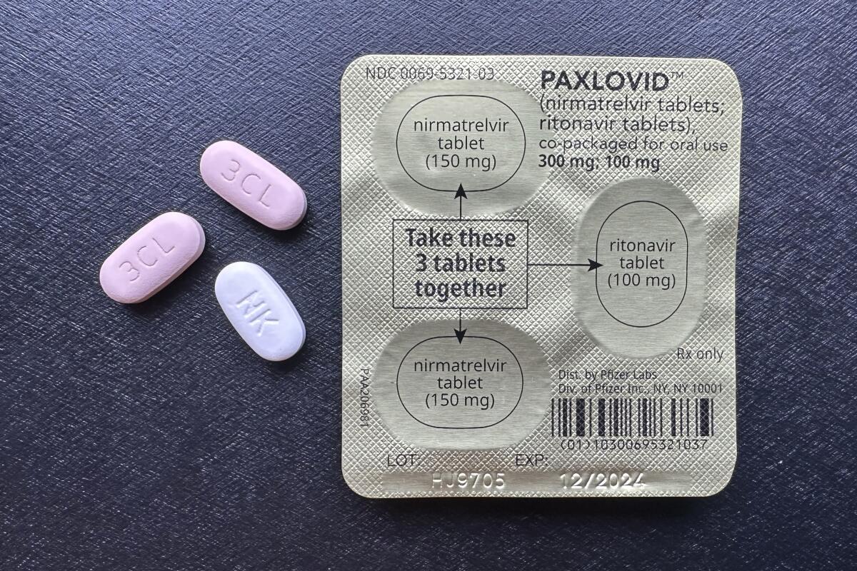 Back of Paxlovid pill package with three pills beside it